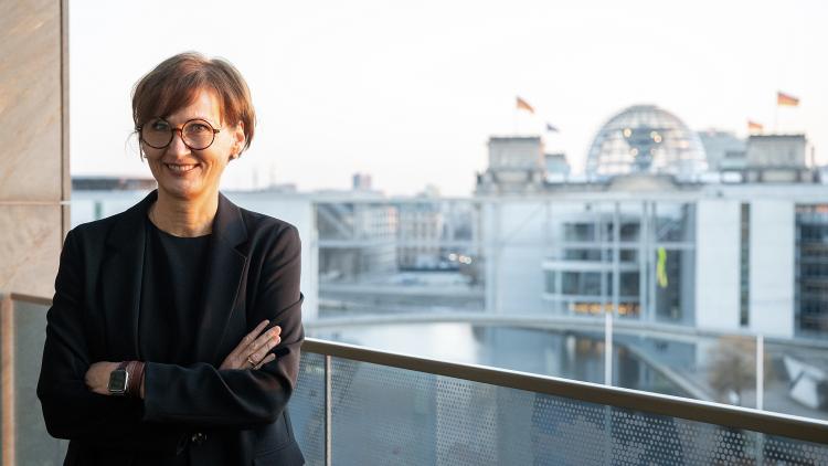 Forschungsministerin Bettina Stark-Watzinger auf dem Balkon des Bundesministeriums für Bildung und Forschung. Im Hintergrund sind das Paul-Löbe-Haus und das Reichstagsgebäude zu sehen.